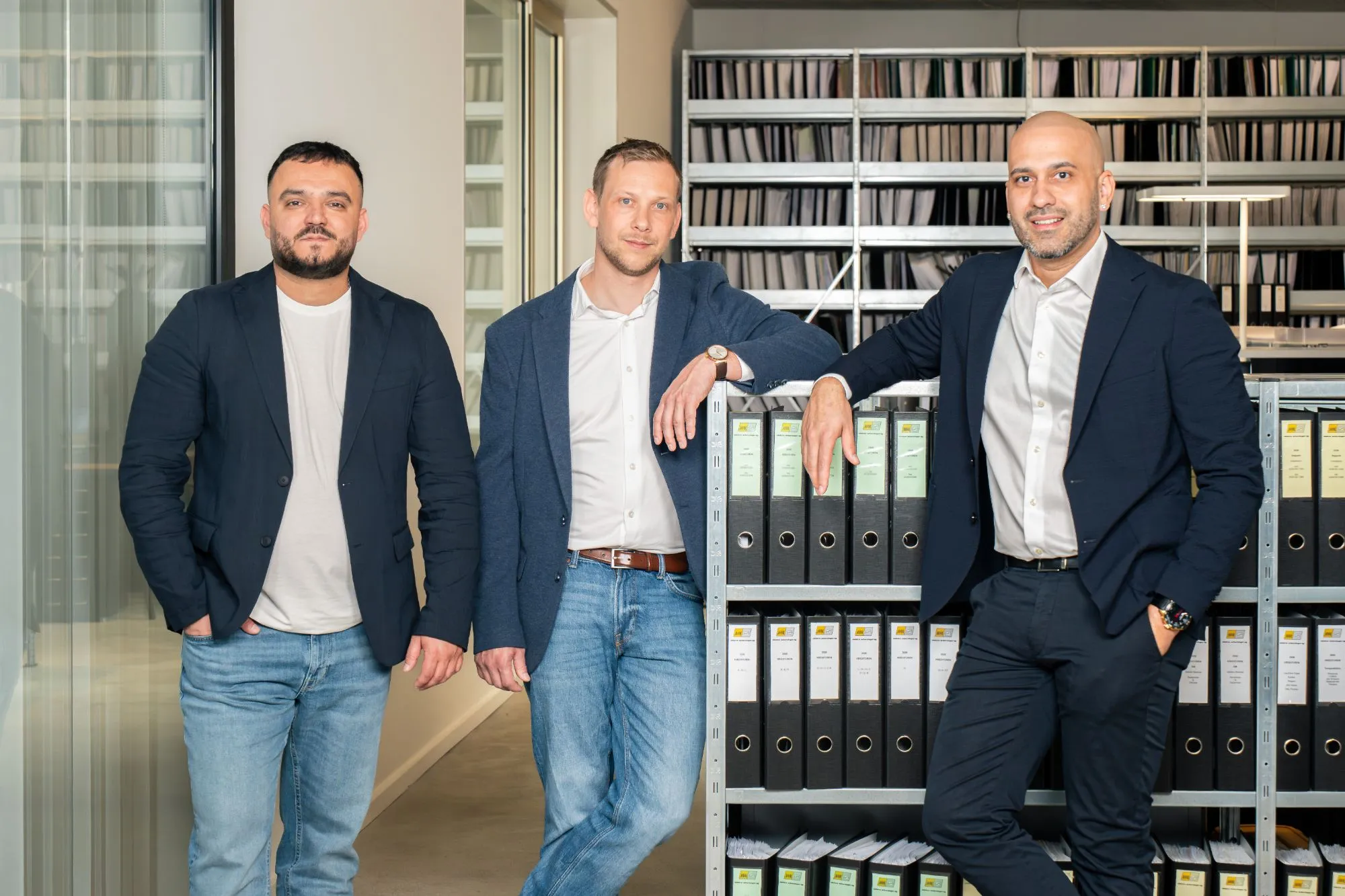 Drei Mitarbeiter von Elektro Scherzinger im Büro vor einem Regal mit Ordnern
